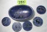 Mixed Lot Vintage Safari Animal Coasters / Bowl
This lot contains a matching set of 5 stoneware coasters and a decorative dish / bowl. Each piece has a blue background and features a different exotic animal. The bowl has a giraffe and an elephant, the coasters have a zebra, hippopotamus, lion, zebra, antelope and a gnu. The coasters are approximately 3" in diameter. The dish measures 1.5" tall and 8" across
