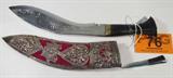 Vintage "Kurkha" Knife with Elaborate Sheath
This lot is a vintage curved blade knife and elaborately decorated sheath. One side of the knife blade is etched with a dragon figure and the other side has five different symbols etched into it. The sheath has magnificent silver color filigree style embellishments which feature images of peacocks, an elephant and a butterfly. A small knife located in the back of the sheath is used to sharpen and maintain the blade. The Kurkha knife measures approximately 14" from tip to tip. The small knife measures 4" long.
From the internet: "The kukri is a curved Nepalese knife, similar to the machete, used as both a tool and as a weapon. It is a traditional weapon for Nepalese people, and also a weapon of choice/side arm for all Nepalese including those serving in different armies around the world. The cutting edge is inwardly curved in shape and is the icon of Nepal. It was, and in many cases still is, the basic and traditional utility knife of the Nep