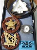 Mixed Lot Southwestern Style Belt Porcelain Dish +
Mixed lot of Southwestern style items bearing freemason / masonic symbols. Includes:
- Leather belt, tanned & engraved with the freemason symbol of a square and compass with a capital "G" in the center. 7 belt holes, measures 43" long and 1.5" wide. 
- Carved wooden hanging wall plaque, circular shaped, brown with an off white / ivory color freemason symbol in the center, Square & Compass with a capital "G" in the center, other symbols carved around the brown edges. Measures 4.25" in diameter. 
- Carved wooden wall hanging plaque, circular shaped, brown edge with an off white / ivory colored symbol carved in the center. Symbol of the Order of the Eastern Star. Smaller symbols carved throughout the star, floral images carved around the circular border. The word "FATAL" is spelled with a letter positioned at each of the five points of the star. Exquisite details. Measures 4.25" in diameter. 
- Silver colored belt buckle with a white inla
