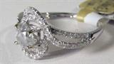 Jewelry 18KT White Gold Diamond Ring AIG
Breathtaking 18KT white gold ladies diamond ring, fits a finger size 7.0. Included American International Gemologists (AIG) Report reads:
"One electronically tested 18KT white gold ladies cast diamond ring. Condition is new, good workmanship. The Featured diamond is set within a tiered diamond frame, supported by diamond set shoulders and completed by a two millimeter wide band. Bright polish finish. Identified with markings of "18K 720". Containing:
One prong set round brilliant cut diamond, measuring 5.40 - 5.20 x 3.50mm, 5.00% GTFC approximate weight of 0.65 ct. with a strong blue fluorescence. Graded in the setting. 
Clarity: I-2
Color: G
Depth: 66.0%
Table: 54.7%
Sixty-six prong set single cut diamonds measuring 1.10 - 1.00 x 0.63mm (depth estimate) approximate total weight of 66 stones = 0.26ct. Graded in the setting. 
Clarity: SI-2 to I-1
Color: F-H
Total weight of diamonds: 0.91ct
Total weight of ring: 3.11gm."

ZB2940
