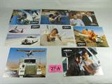 Art 8 French Posters "James Bond: License to Kill"
Lot of 8 James Bond 007: Permis de Tuer (License to Kill) promotional mini posters. Each depicts a scene from the 1989 film starring Timothy Dalton as Agent 007, Carey Lowell and more. Scenes included are:
- James Bond (Dalton) and Pam Bouvier (Lowell), embracing in a pool
- Character Lupe Lamora (played by Talisa Soto), dressed in white sitting on a couch, looking up from reading a book 
- Two men, appearing to be henchmen, one holding an iguana, the other wearing a tuxedo
- A semi-truck exploding on a desert highway
- James Bond (Dalton) and Pam Bouvier (Lowell), an action shot, they appear to be navigating and flying a crop-duster style airplane. 
- A stunt shot of James Bond dropping from a crop duster style airplane onto the back of a moving semi-truck
- Pam Bouvier (Lowell) standing by a pool in a blue flowing strapless gown, staring off into the distance. Behind her, Agent 007 is free falling into the pool behind her, the shot c