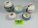 Lot of 5 Southwest Native American Indian Pottery
This lot includes five southwestern style vases / bowls, all appear to have been hand made by Native American Indians. Lot includes:
- A small vase with beautiful etchings near the top and a colorful striped bottom. Signed "Tsosie - Navajo". Measures 2.5" tall.
- A small bowl with a black and blue geometric pattern around the top. The piece has an undetermined signature on the bottom. Measures 2" tall with a 4" diameter.
- A baby blue bowl with two pink stripe accents. Inside of bowl has a glazed finish. Bottom is marked "F - 89".
Measures 2.75" tall x 4.5" in diameter.
- A pretty white and mauve color vase with feather designs on the outer surface. Vase has a hole near the top rim where a leather strap has been attached. The leather strap is decorated with beads and feathers. Bottom is signed "Little Violet '64". Measures 5" tall.
- A beautifully decorated vase featuring a scene of an Indian tepee shadowed against a background of snow