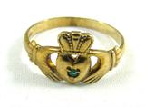 Jewelry 9KT Yellow Gold Claddagh Ring "Sold'Or"
Adorable 9KT yellow gold Irish Claddagh ring. Features two hands holding a heart that is wearing a crown. Small green gemstone in the center, possibly emerald. Marked / signed "Made in Ireland 375".
From CladdaghRing.com:
"The Claddagh's distinctive design features two hands clasping a heart, and usually surmounted by a crown. The elements of this symbol are often said to correspond to the qualities of love (the heart), friendship (the hands), and loyalty (the crown). The way that a Claddagh ring is worn on the hand is usually intended to convey the wearer's romantic availability, or lack thereof. Traditionally, if the ring is on the right hand with the heart facing outward and away from the body, this indicates that the person wearing the ring is not in any serious relationship, and may in fact be single and looking for a relationship: "their heart is open." When worn on the right hand but with the heart facing inward toward the body, t