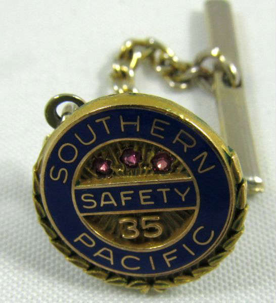Jewelry Southern Pacific Service Pin 35 Years
- A Southern Pacific Railroad 25 years of safety service tie tack featuring three red stones. Back is marked "1/10 10kt".
For more Southern Pacific award pins see lots 53, 131, 192, 289, 339, and 394 in this auction.

Z14