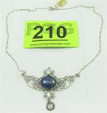 Jewelry Sterling Nouveau Lapis Moonstone Necklace
Stunning sterling silver fashion necklace, nouveau style, featuring a larger blue Lapis stone, smooth / cabochon style, in a silver bezel, with three small white moonstones, smooth / cabochon style, in individual silver bezels. Stones are arranged vertically with the largest stone as the centerpiece, consignor states all gemstones are genuine. Flanked by sterling silver Celtic knot style designs, with a Figaro style chain that completes with a spring ring clasp. Truly beautiful design. Marked / signed "925", measures 22.5" long.
Total weight: 0.83 ozt