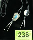 Jewelry Lot of 2 Sterling Bolo / Bola Ties
A great lot of two southwestern style sterling silver bolo / bola ties:
- An oval slide featuring an oval polished agate stone. Back is marked "Emily - Handcrafted". Tests as sterling silver. Mounted to a 35" braided black leather tie.
- A trapezoid shaped slide featuring an etched southwestern design with a turquoise stone center setting. Mounted to a 36" braided black leather tie. Tests as sterling silver. Back is marked "Bennett - Patent Pending".
Total weight: 1.5 ozt.