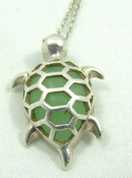 Jewelry Sterling Silver Sea Turtle Pendant
Darling sterling silver necklace with sea turtle shaped pendant accented with a green gemstone, possibly jade. Marked "925", measures: 16" long. Total weight: .14 ozt.