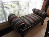 Bench with rolled and curled arms, stiiped upholstery.