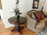Marge Carson: Parlor table with distressed wood, tall floral arrangement.
