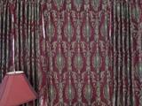 Several curtain panels. Floor to ceiling. Rich burgundy and gold fabric.