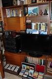 Teak bookcase/entertainment center with sliding doors. Apex flat screen TV, stacking stereo components, 8 track tapes and cassettes, DVDs, VHS tapes and CDs.