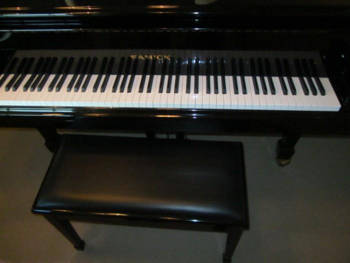Front view of Samick baby grand piano and bench.