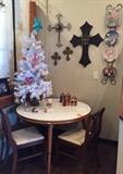 Ornaments and crosses on top of a mid-century dining table and two chairs.