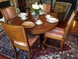 Antique oak table with 6 chairs (4 shown) and 3 leaves atop a lovely Oriental rug.