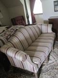 Camel back sofa upholstered in tones of beige/green stripes