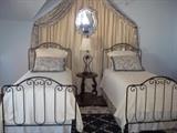 Pair of wrought iron twin beds, foundations, pillows, spreads, and wall treatment.  also a round side table and lamp.