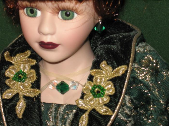 Doll in glass case. Camellia Gardens 16 inch porcelain doll featuring authentic "Swarovski" necklace and earrings.