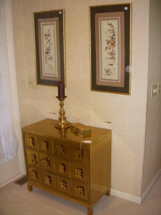 Mastercraft brass covered 3-drawer chest.  Framed Chinese silk embroideries on wall.