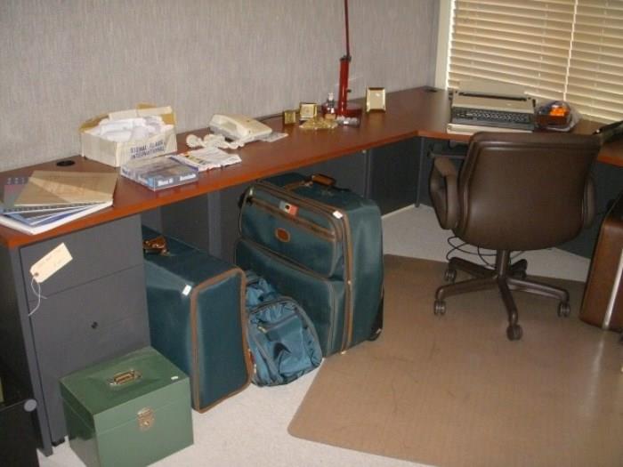 Corner office desk, chair, luggage, electric typewriter, etc.