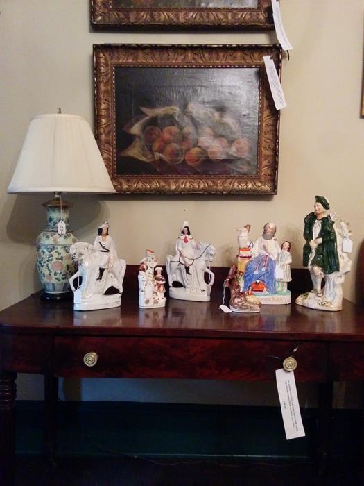 Group of fine antique Staffordshire figures, including large man with bagpipe at far right. Two early American still life paintings above with original frames.