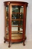 124 - Oak curved glass china cabinet with original finish, claw feet and glass shelves, 65 in. T, 36 in. W.
