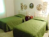 Twin Brass Beds with Mattresses and Decorative Wall Hangings