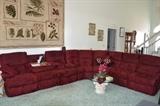 Maroon sectional featuring reclining chairs and a fold down table with drink holders. Glass top coffee table