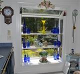 Blue glass accent pieces and dishware, wall clocks, floral decor