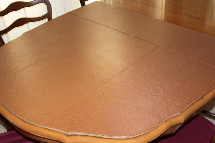 Oval dining table with partial pad.