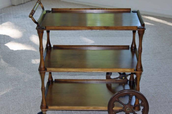This three shelf Tea Cart is in very good condition. Has a protective glass on the top shelf. The front wheels are small and the back wheels are ornate wood.
