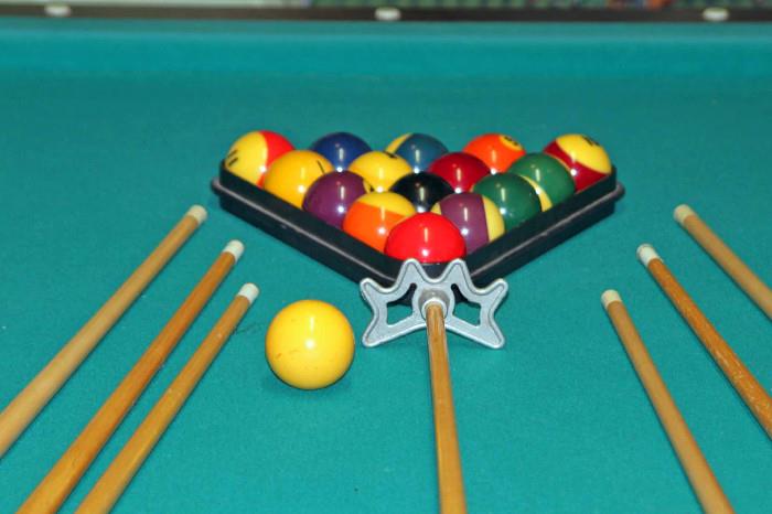 Pool table made with slate. Includes rack, brush, set of balls, six cues and an assistant cue. Bring tools for dismantling. 