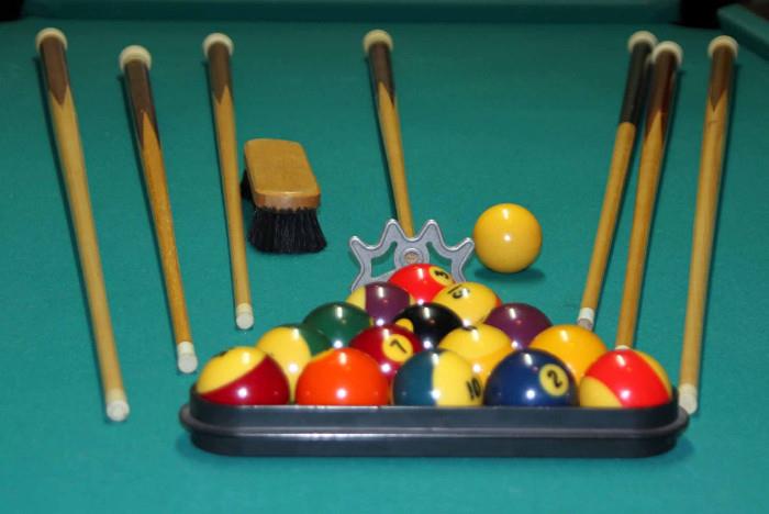 Pool table made with slate. Includes rack, brush, set of balls, six cues and an assistant cue. Bring tools for dismantling. 