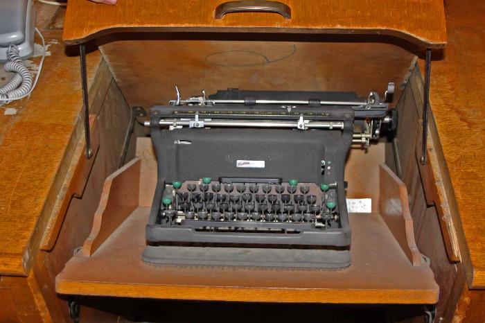 Typewriter is revealed as the middle portion of the desk top is rolled back. Mechanism is in good working order.