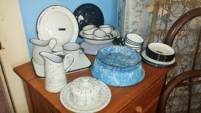 Hand made pine table, enamelware including blue swirl pie plate, pan; black & white plates, cups/saucers, pitcher, bowl, & tea infuser; pattern enamelware covered butter dish & cream pitcher.