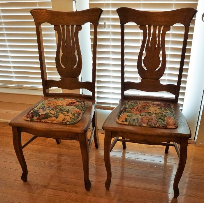 Two of the 12 matching oak dining chairs