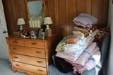 Five drawer chest with mirror, wingback chair and assorted linens.