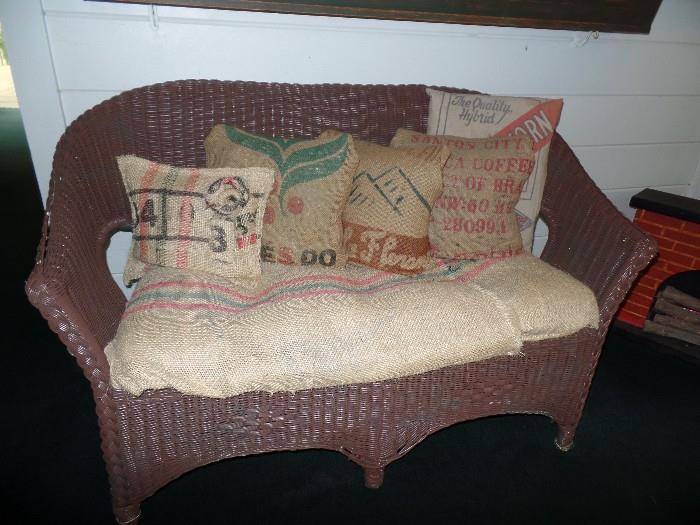 Vintage wicker love seat with burlap cushions and pillows 