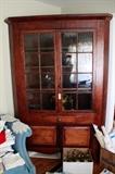 c.1800 VA Cherry Corner cupboard, with early glass lite doors open to three shelves over single center drawer resting on pair of raised panel tiger maple doors, case ending in boot jack feet and curved apron. Hand pegged and square nail constuction, warm mellow finish.