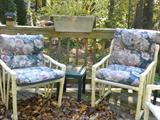 Two of a set of outdoor chairs with floral cushions.