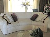 One of a pair of curved white jacquard/brocade sofas.