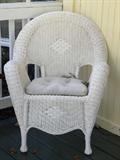One of a pair of outdoor wicker chairs.