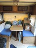 Camper/trailer interior, sleeps 3-4, with kitchenette (sink, cabinets, stove, refrigerator), dinette seating, bath and furnace. Priced to go!