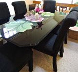 Elegant seven piece contemporary dining set in basic black. Glass top table (shown here with floral table runner), and six rich black side chairs upholstered in a textured slubby fabric.