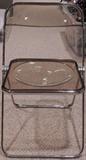 One of three smoke lucite-type folding chairs.