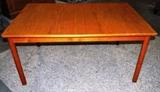 Item Description: A wonderful Mid Century Danish Modern teak dining table with a sleek clean classic style featuring a rectangular top with rounded edges which separates to center revealing two hidden fold out leaves for added space. The top rests on four cylindrical legs.