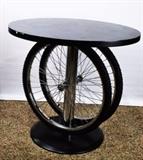 Item Description: Upcycling meets Modern Industry with this funky cyclist inspired table featuring a black painted wooden circular top and base with chrome tone metal pedestal flanked by bicycle rims and tires.