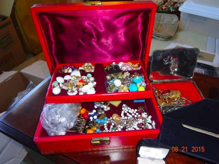 A red jewelry box with numerous pieces.