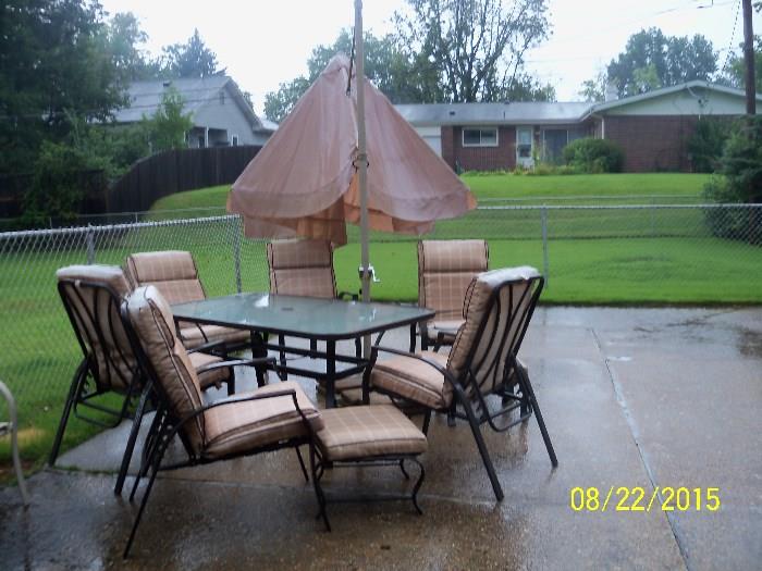 Patio table with 6 chairs 2 footstools and a market umbrella  (cushions are faded, but price is right)