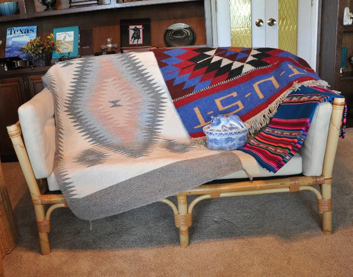 Mid century (1960s) rattan 2 seat settee displaying 2 rugs - settee has been stored and needs to be recovered as there is damage to the fabric on the seat cushions.