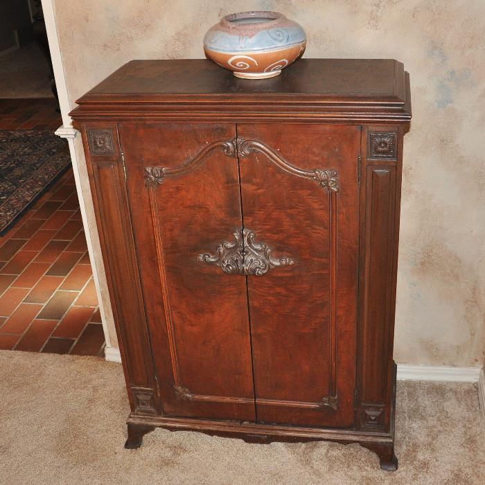 An antique radio cabinet that now serves as a storage cabinet.